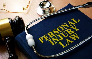 Personal Injury Law book, a stethoscope and a judge's gavel on a desk of a medical malpractice attorney.